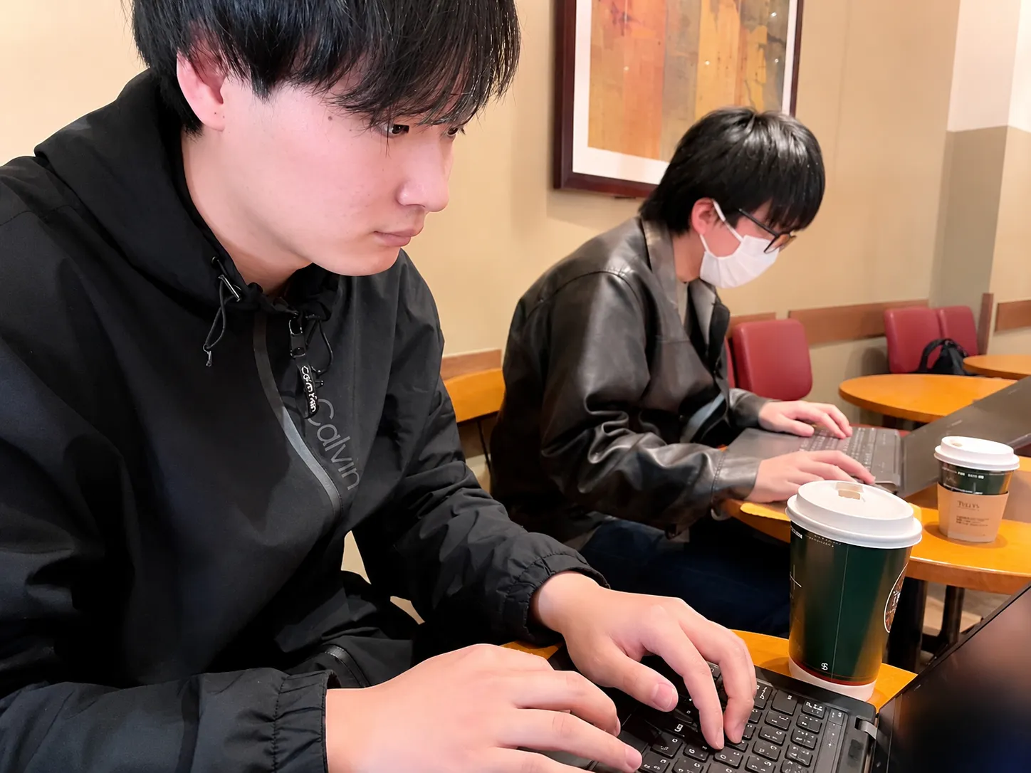 カフェで2名がパソコンを使ってWebサイトを制作している様子